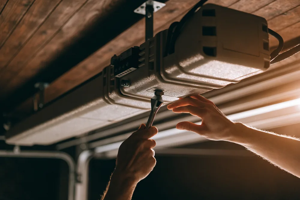 A technician servicing a garage door opener motor unit
